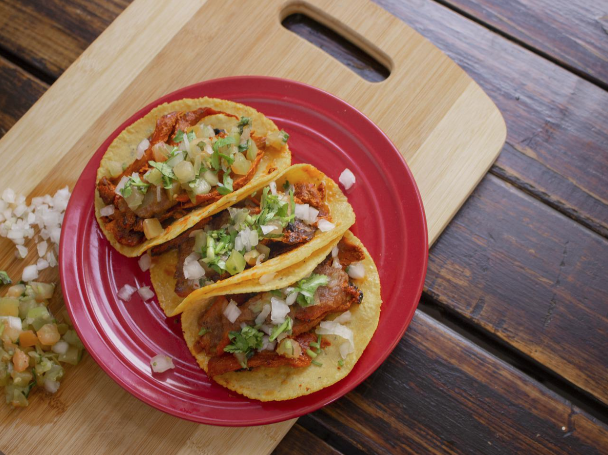 meat and onions tacos on a red plate